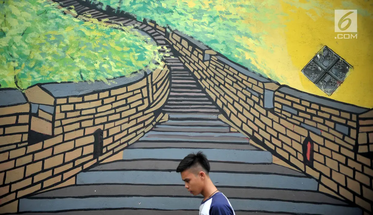 Seorang pria berjalan di Kampung Warna Warni Lubuklinggau, Sumatera Selatan, Rabu (10/1). Saat ini kampung tersebut telah disulap menjadi tempat wisata baru di Lubuklinggau. (Liputan6.com/Immanuel Antonius)