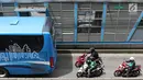 Pengendara motor melaju di belakang bus Transjakarta di kawasan Pasar Rumput, Jakarta, Rabu (20/2). PT Transportasi Jakarta akan memasang kamera pengawas (CCTV) di setiap halte untuk menerapkan tilang online atau E-Tilang. (Liputan6.com/Immanuel Antonius)