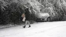 Seorang perempuan melintasi jalan yang tertutup salju di Beograd, Serbia, Minggu (12/12/2021). Ahli meteorologi memperkirakan hujan salju lebat dan suhu di bawah nol di Balkan Barat sepanjang minggu. (AP Photo/Darko Vojinovic)