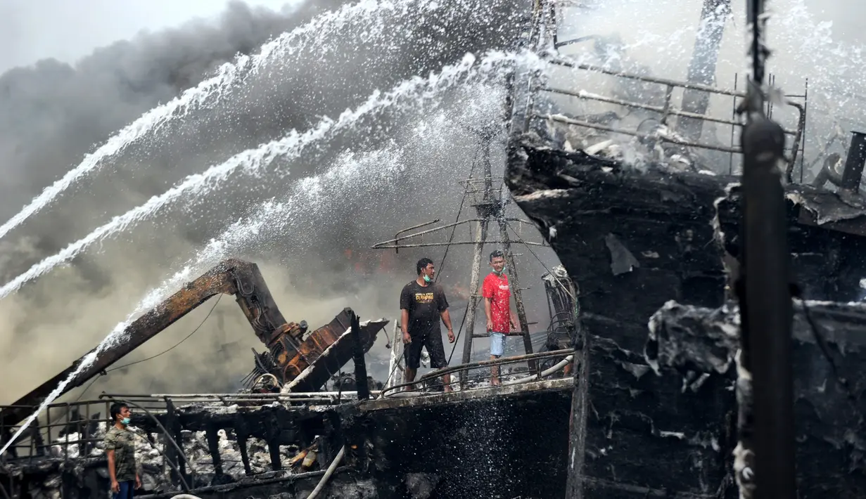 Para pekerja mencoba membantu memadamkan api di kapal nelayan di Pelabuhan Benoa, Denpasar, Bali, Senin (9/7). Hingga kini pemilik kapal masih belum bisa dimintai keterangan. (SONNY TUMBELAKA/AFP)