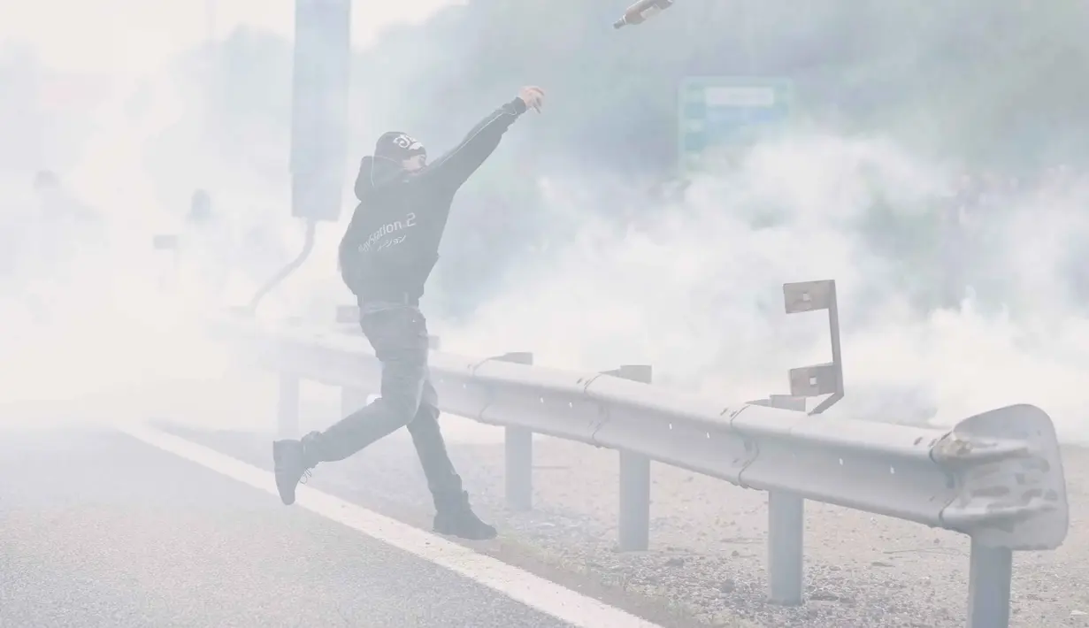 Bentrokan singkat sempat terjadi ketika sekelompok demonstran yang memblokade jalan tol kota mulai melempari polisi dengan botol dan polisi membalas dengan bom asap. (AP Photo/Luca Bruno)