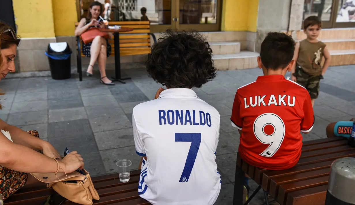 Anak laki-laki yang mengenakan kaus Real Madrid dan Manchester United duduk di bangku di Skopje pada 8 Agustus 2017 menjelang pertandingan sepak bola UEFA Super Cup antara Real Madrid dan Manchester United. (AFP Photo/Armend Nimani)