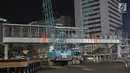 Petugas merobohkan Jembatan Penyeberangan Orang (JPO) di Kawasan Bundaran Hotel Indonesia, Jakarta, Senin (30/7) malam. JPO dirobohkan karena menghalangi pandangan ke patung Selamat Datang yang terletak di tengah bundaran HI (Liputan6.com/Herman Zakharia)