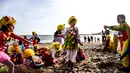 Anak-anak dengan pakaian badut bermain di pantai selama parade badut tahunan di Sesimbra, Portugal pada Senin (4/3/2019). Tidak hanya orang dewasa anak-anak pun ikut merias diri menjadi badut. (PATRICIA DE MELO MOREIRA / AFP)