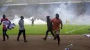 Polisi menembakkan gas air mata untuk mengejar penyerbu lapangan pada akhir pertandingan kualifikasi Piala Dunia 2022 antara Ghana Vs Nigeria di Stadion Moshood Abiola, Abuja, Nigeria, 29 Maret 2022. Fans Nigeria ngamuk setelah gagal lolos ke Piala Dunia 2022. (AP Photo/Sunday Alamba)