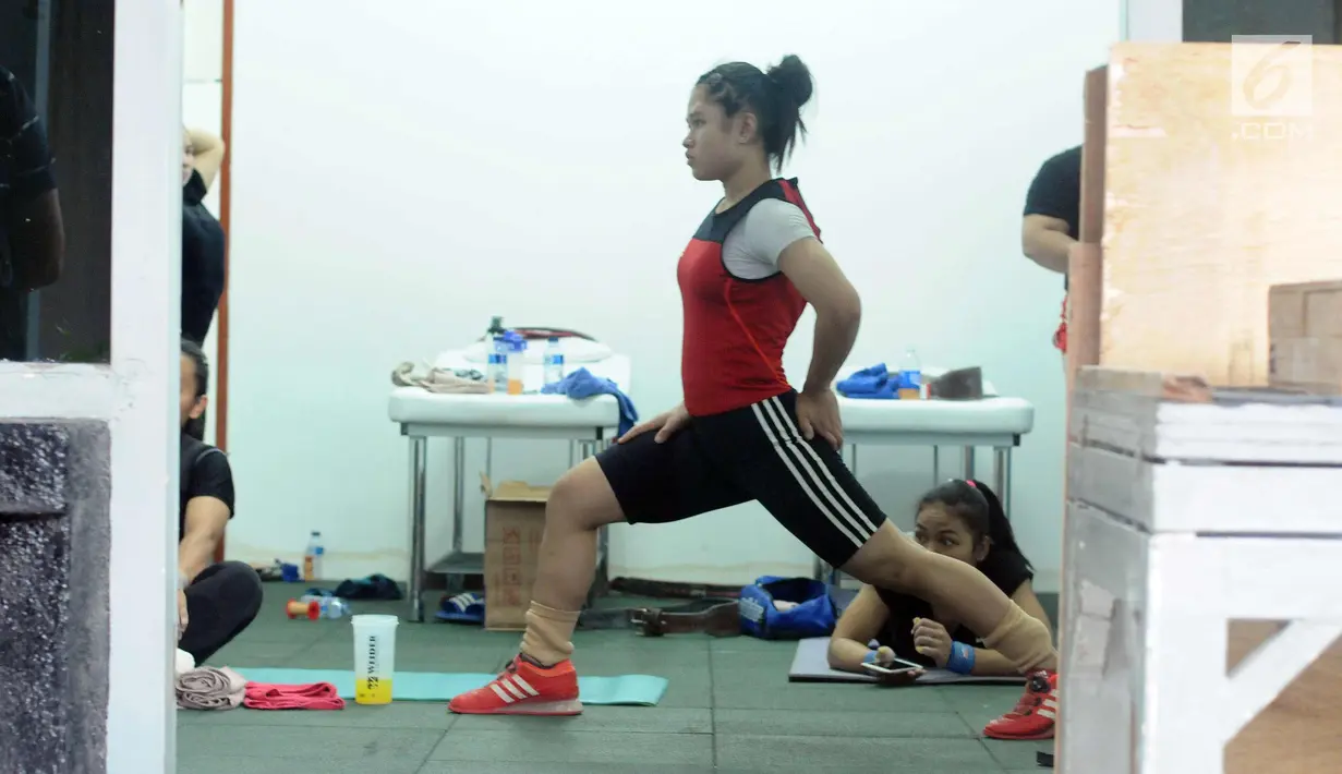 Salah satu lifter putri Indonesia melakukan pemanasan disela-sela latihan tes prestasi pelatnas angkat besi Asian Games 2018 di Mako Lanmar Jakarta, Selasa (6/3). Tes ini mengukur kemajuan atlet jelang Asian Games 2018. (Liputan6.com/Helmi Fithriansyah)