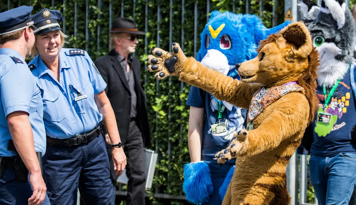 Peserta mengenakan kostum binatang mengajak polisi untuk berpelukan saat parade konvensi Eurofurence di Berlin, Jerman (17/8). Dalam acara peserta mengenakan kostum hewan berbulu. (AFP Photo/Ganjil Andersen)