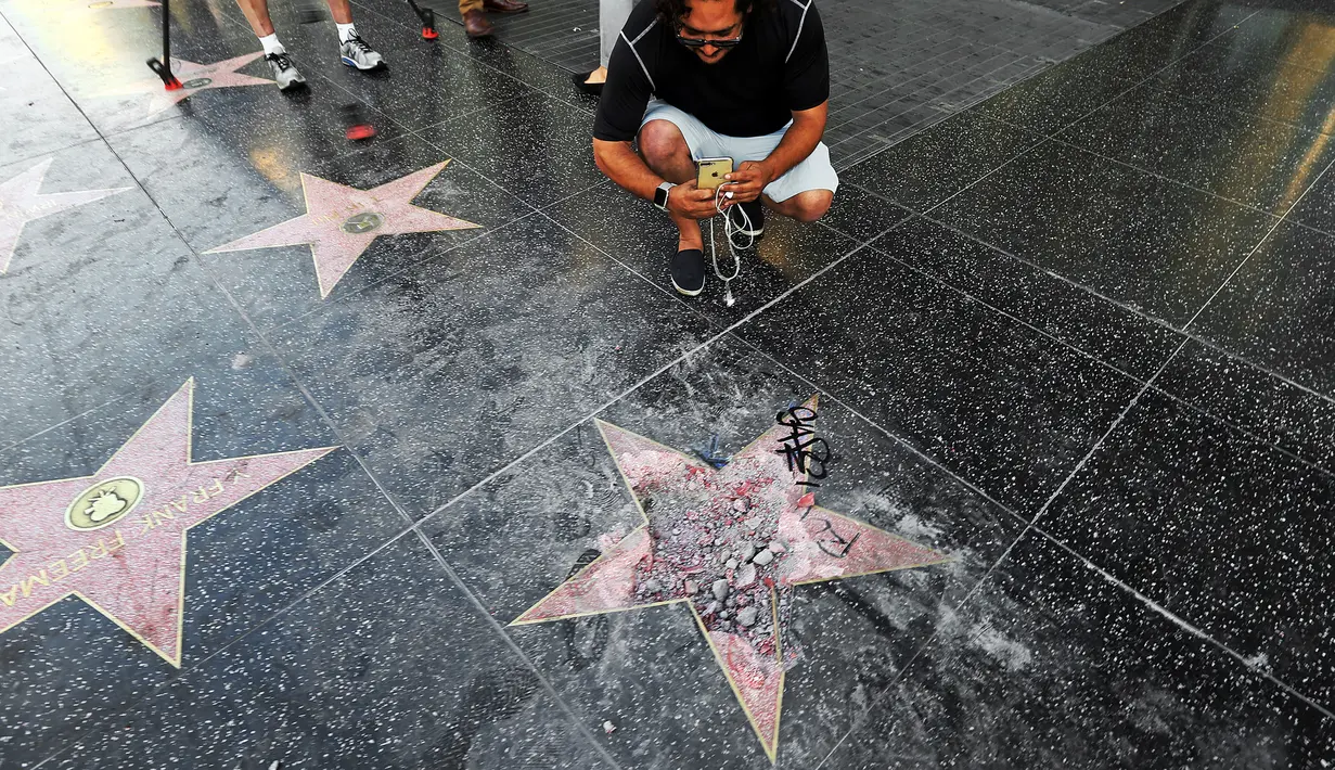 Pengunjung mengambil gambar bintang di Walk of Fame Hollywood atas nama Presiden AS Donald Trump yang dirusak seorang pria, di Los Angeles, Rabu (25/7). Bagian tengah bintang yang berwarna merah itu telah menjadi serpihan pasir dan batu. (AP/Reed Saxon)
