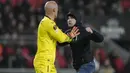 <p>Seorang suporter fanatik PSV berusaha menyerang kiper Sevilla, Marko Dmitrovic dalam laga leg kedua babak playoff fase gugur Liga Europa 2022/2023 di Philips Stadium, Eindhoven, Jumat (24/2/2023). (AP Photo/Peter Dejong)</p>