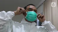 dr Rahmadi Iwan Guntoro, Sp.P melapisi masker N95 dengan masker bedah di Rumah Sakit Haji, Jakarta, Kamis (9/4/2020). Gugus Tugas Percepatan Penanganan COVID-19 telah mengeluarkan rekomendasi standar APD berdasarkan tiga tingkatan perlindungan. (Liputan6.com/Herman Zakharia)