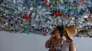 Pengunjung melihat instalasi seni yang terbuat dari sisa-sisa plastik, kaleng dan wadah di sebuah pameran "Reduce the Litter" di Hanoi (15/7/2019). Pameran ini menggambarkan polusi dari limbah rumah tangga yang menyebabkan dampak berbahaya bagi lingkungan dan kesehatan anak. (AFP Photo/Nhac Nguyen)