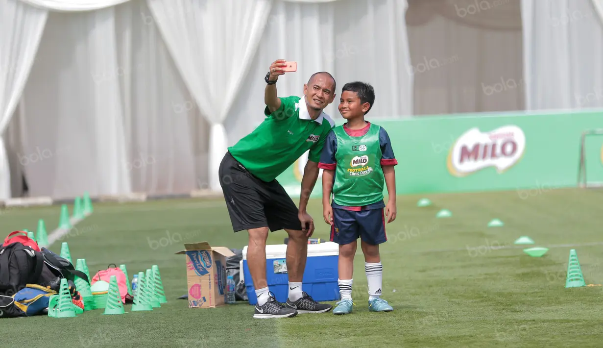 Kurniawan berfoto selfi dengan seorang siswa saat mengikuti ajang Milo Football Clinic Day, Minggu (30/10/2016) di Simprug. (Bola.com/Nicklas Hanoatubun)