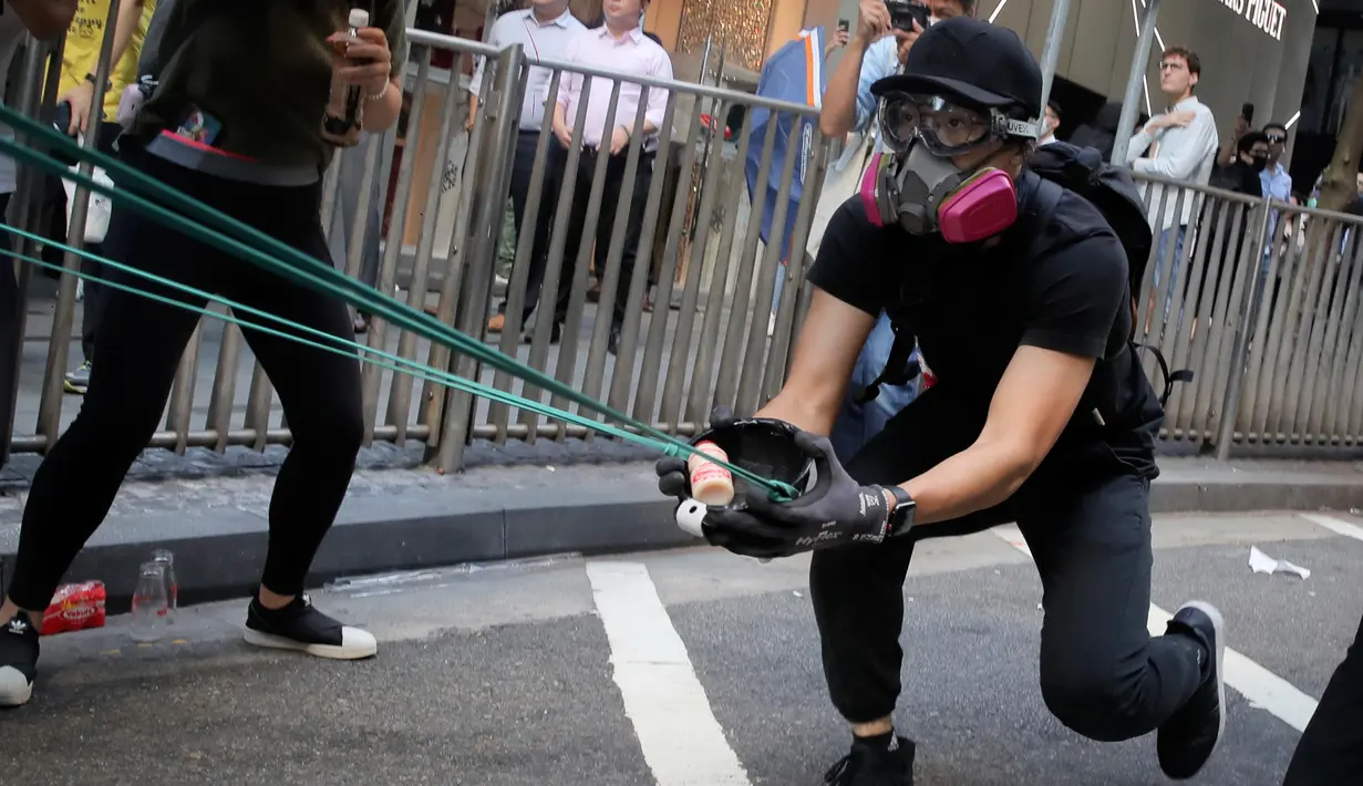 Demonstran menembakkan susu kemasan menggunakan sling shot ke arah polisi saat demonstrasi di Hong Kong, Senin (11/11/2019). Ketegangan di Hong Kong semakin meningkat setelah polisi menembak seorang demonstran hingga kritis. (AP Photo/Kin Cheung)