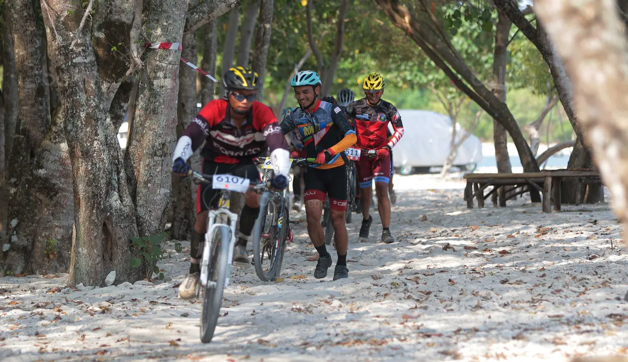 Para pebalap melintasi trek berpasir Mountain Bike Cross Country Marathon pada Festival Pesona Tanjung Lesung 2017 di Tanjung Lesung, Banten (23/9/2017). MTB XCM tersebut menempuh jarak 48 km. (Bola.com/Nicklas Hanoatubun)