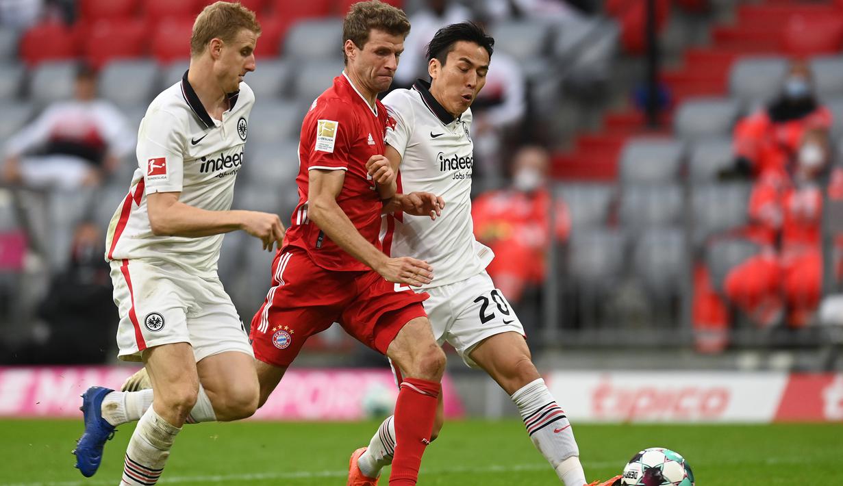 Penyerang Bayern Munchen, Thomas Mueller, berebut bola dengan bek Eintracht Frankfurt, Martin Hinteregger, pada laga lanjutan Liga Jerman di Allianz Arena, Sabtu (24/10/2020) malam WIB. Bayern Munchen menang 5-0 atas Eintracht Frankfurt. (AFP/Christof Stache/various sources)