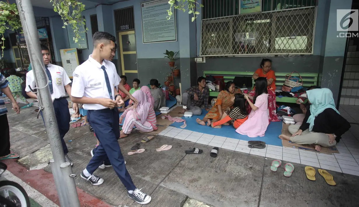 Sejumlah murid beraktivitas di Gedung SMP Negeri 26, Jalan Kebon Pala, Kampung Melayu, Jatinegara, Jakarta Timur, Selasa (6/2). Sebanyak 42 KK mengungsi di tempat tersebut. (Liputan6.com/Arya Manggala)