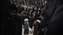 Pria dan anak-anak Yahudi ultra-Ortodoks, beberapa mengenakan kostum membaca Kitab Ester, yang menceritakan kisah festival Yahudi Purim, di sebuah sinagoga di Bnei Brak, Israel, Senin (6/3/2023). Purim dirayakan tiap tahun menurut kalender Ibrani oleh kaum Yahudi. (AP Photo/Oded Balilty)
