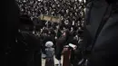 Pria dan anak-anak Yahudi ultra-Ortodoks, beberapa mengenakan kostum membaca Kitab Ester, yang menceritakan kisah festival Yahudi Purim, di sebuah sinagoga di Bnei Brak, Israel, Senin (6/3/2023). Purim dirayakan tiap tahun menurut kalender Ibrani oleh kaum Yahudi. (AP Photo/Oded Balilty)