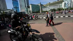 Pasukan Brimob mengendarai motor dan bersenjata lengkap berpatroli saat Car Free Day di kawasan Bunderan HI, Jakarta, Minggu (24/12). Operasi Lilin 2017 ini guna memberikan kenyamanan pada masyarakat. (Liputan6.com/Faizal Fanani)