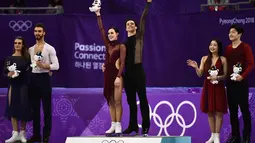 Pasangan Figure Skating Tessa Virtue dan Scott Moir (tengah) berada di podium usai meraih emas pada Olimpiade Musim Dingin Pyeongchang 2018 di Gangneung Ice Arena di Gangneung (20/2). (AFP Photo/Aris Messinis)