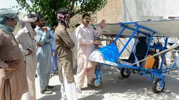 Muhammad Fayyaz berbincang dengan warga yang melihat pesawat buatannya di Desa Tabur, Provinsi Punjab, Pakistan, 8 April 2019. Karya lelaki berusia 32 tahun tersebut berhasil menarik perhatian Angkatan Udara Pakistan. (ARIF ALI/AFP)