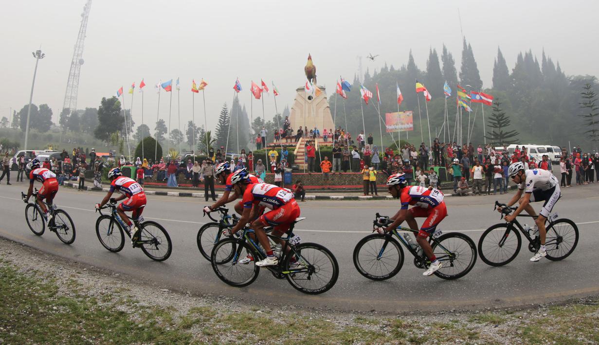 Kabut asap pekat menyelimuti Tugu Ayam di Kabupaten Solok saat lima pebalap Pishgaman Giant Team memimpin dalam Etape 2 Tour de Singkarak 2015, Minggu (4/10/2015). (Bola.com/Arief Bagus)