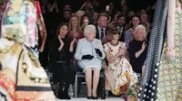 Ratu Elizabeth II duduk di sebelah Anna Wintour dan chief executive British Fashion Council, Caroline Rush menyaksikan London Fashion Week 2018, Selasa (20/2). Ratu Elizabeth datang di hari terakhir London Fashion Week. (Yui Mok/Pool photo via AP)