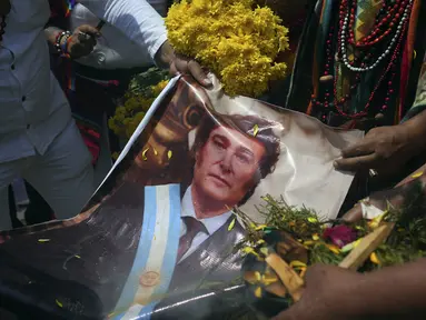 Para dukun memegang foto Presiden Argentina Javier Milei saat mereka melakukan ritual tahunan untuk memprediksi isu-isu politik dan sosial pada tahun baru, di puncak bukit San Cristobal di Lima, Peru, Rabu, 27 Desember 2023. (AP Photo/Guadalupe Pardo)