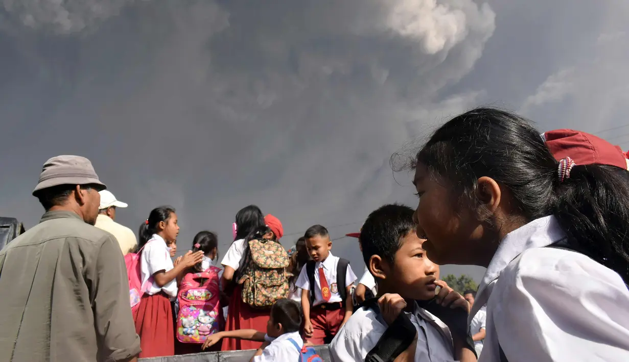 Anak-anak menaiki mobil saat terjadi erupsi Gunung Sinabung di sekolah dasar Sipandak di desa Tiga Pancur di Karo, Sumatra Utara (19/2). Gunung Sinabung aktif kembali tahun 2010 untuk pertama kalinya dalam 400 tahun terakhir. (AFP Photo/Anto Sembiring)