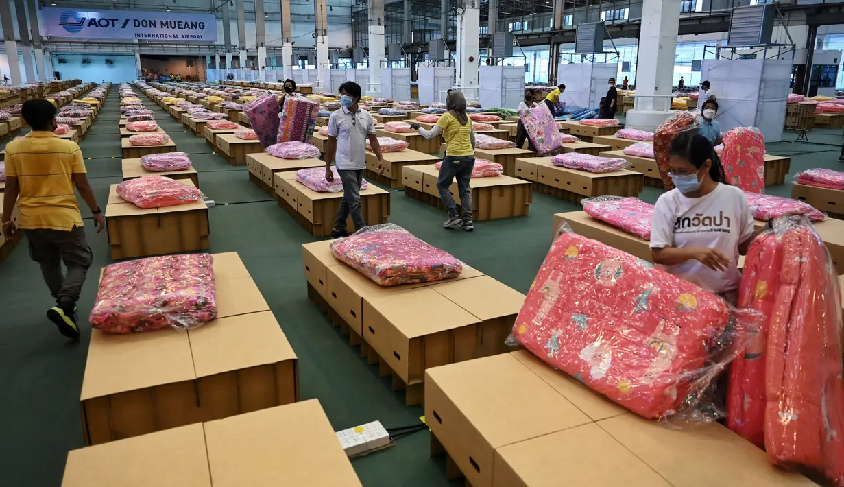 Pekerja menyiapkan kasur dan selimut untuk tempat tidur kardus di rumah sakit lapangan Covid-19 di dalam gudang Bandara Internasional Don Mueang di Bangkok, Selasa (27/7/2021). Thailand menghadapi rekor jumlah kasus virus corona di tengah kampanye vaksinasi yang lambat. (Lillian SUWANRUMPHA/AFP)