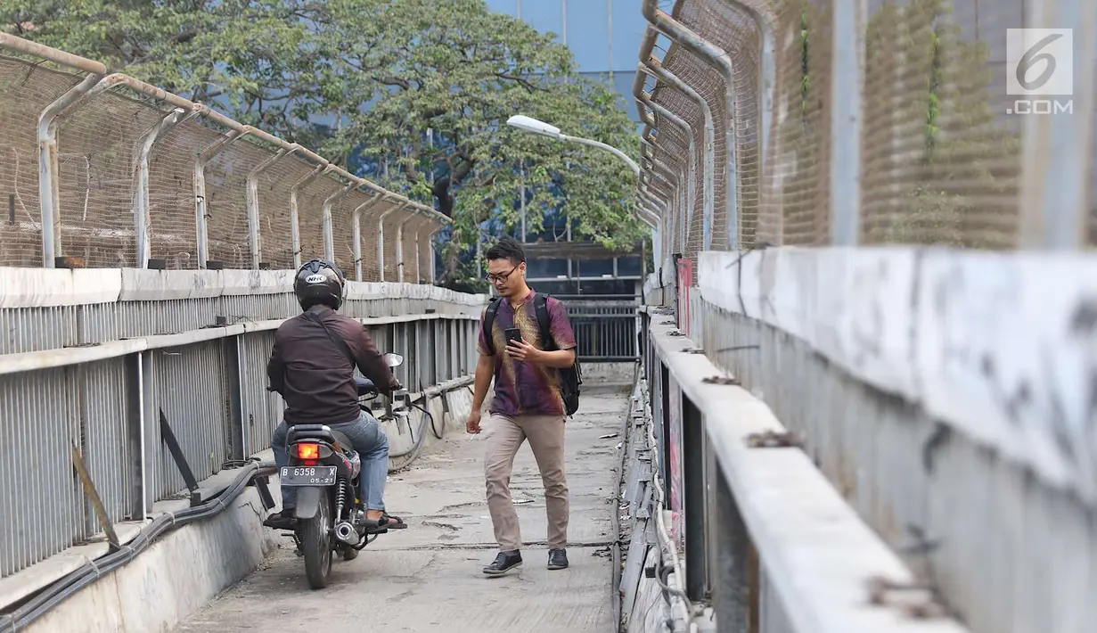 Pejalan kaki melintasi jembatan penyeberangan orang tanpa atap dan tidak terawat di Jalan TB Simatupang, Jakarta, Rabu (10/10). Kondisi tersebut menyebabkan JPO terkesan kumuh serta mengurangi kenyamanan pejalan kaki. (Liputan6.com/Immanuel Antonius)