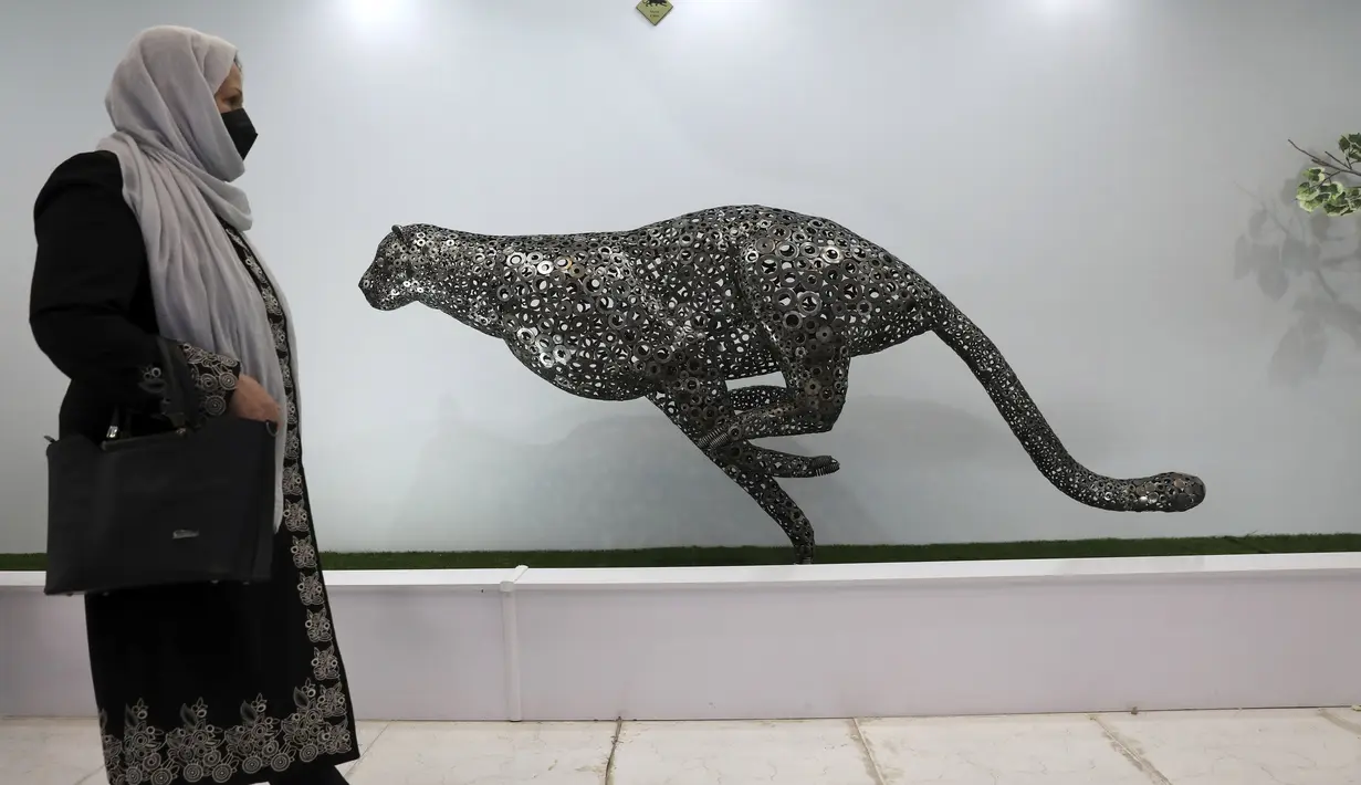 Pengunjung melewati patung cheetah dari mesin cuci besi tua di area indoor Shahreza Metal Zoo di pusat kota Shahreza sekitar 425 kilometer selatan ibu kota Teheran, Iran pada 13 Oktober 2021. Kebun binatang tersebut menampung 30 patung hewan dengan berbagai ukuran. (AP Photo/Vahid Salemi)