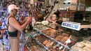 Seorang nudis membeli kue saat mengikuti acara Nude Love Parade di San Francisco, California, AS, Minggu (17/3). Kaum nudis mempraktikkan, menganjurkan, dan mempertahankan pergaulan telanjang dalam lingkungan pribadi maupun umum. (Josh Edelson/AFP)