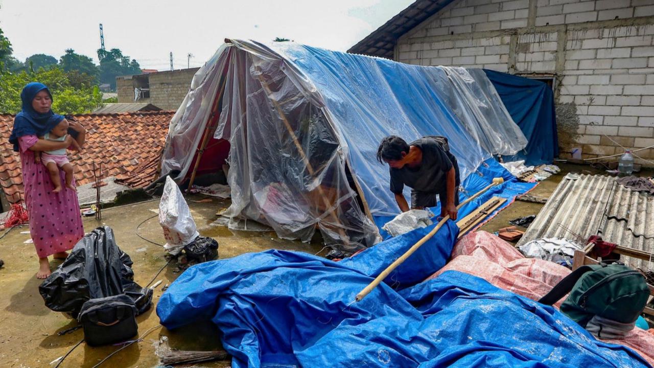 Warga beraktivitas saat akan mendirikan tenda darurat yang dibangun di atas rumah pasca banjir melanda kawasan Pejaten Timur, Jakarta Selatan, Senin (08/01/2024).