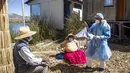 Seorang petugas kesehatan berbicara kepada penduduk pulau Uros, di danau Titicaca di Puno, Peru, pada 7 Juli 2021. Peru memulai vaksinasi COVID-19 untuk ratusan penduduk asli yang tinggal di pulau terapung Uros, di Danau Titicaca. (Carlos MAMANI / AFP)