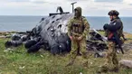 Tentara Ukraina berdiri dengan latar belakang helikopter militer Rusia yang rusak di Pulau Ular, Laut Hitam, Ukraina, 18 Desember 2022. Pasukan Rusia menduduki pulau itu pada awal-awal invasinya ke Ukraina, namun akhirnya mundur beberapa bulan kemudian. (AP Photo/Michael Shtekel)