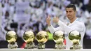 Bintang Real Madrid, Cristiano Ronaldo, berpose dengan kelima trofi Ballon d'Or di Stadion Santiago Bernabeu, Sabtu (9/12/2017). Cristiano Ronaldo meraih Ballon d'Or 2017 setelah unggul dari Lionel Messi dan Neymar. (AFP/Pierre-Philippe Marcou)
