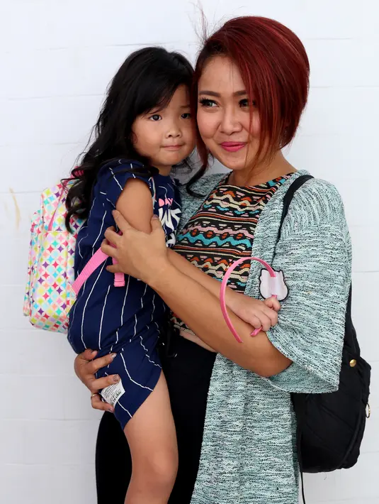 Cici Panda tampil fresh dengan tatanan rambut yang dipotong pendek dan diwarnai dengan cat rambut berwarna coklat kemerahan. Ia menggendong kesayangannya yaitu Alika yang tampak bersender manja dengan sang mama. (Andy Masela/Bintang.com)