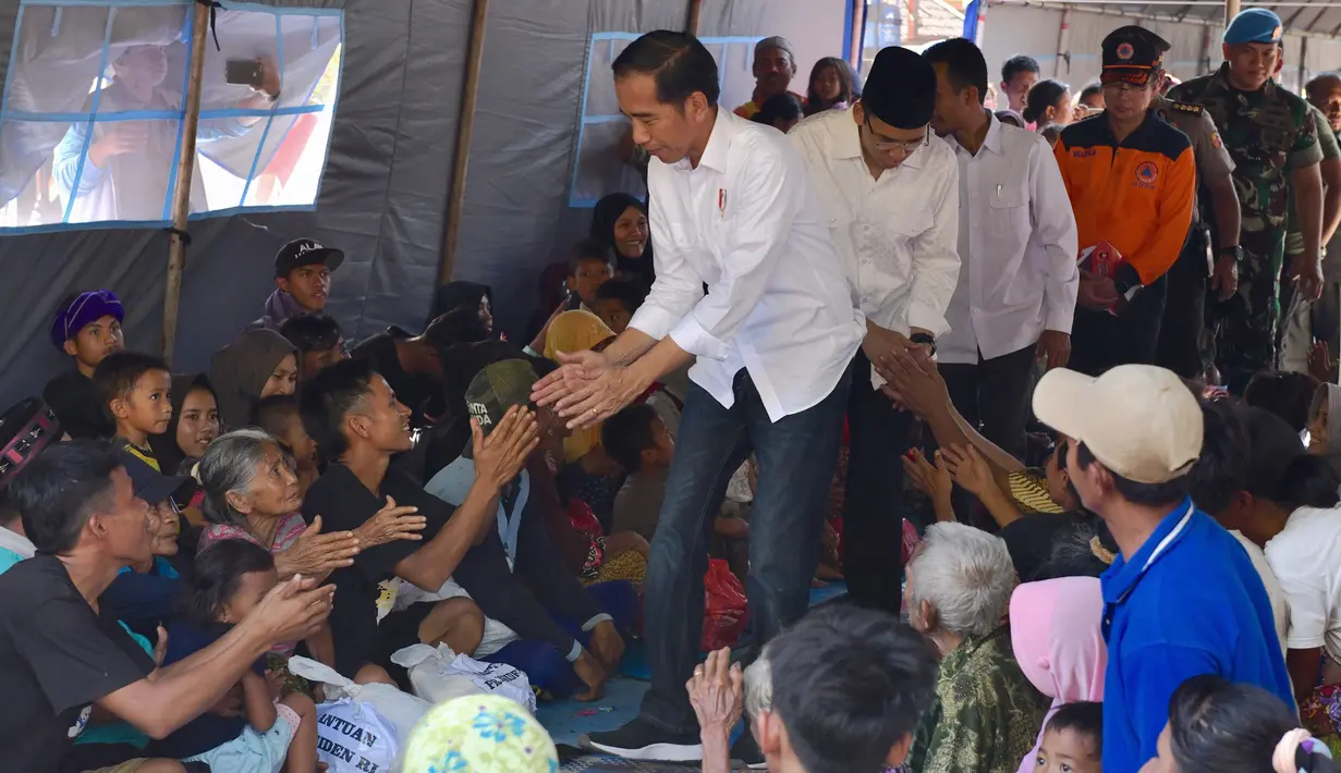 Presiden Joko Widodo atau Jokowi bersama Gubernur NTB Tuan Guru Bajang (TGB) Zainul Majdi menyapa warga saat mengunjungi korban gempa di lapangan Desa Madayin, Sambelia, Lombok Timur, NTB, Senin (30/7). (Agus Suparto/Indonesian Presidential Palace/AFP)