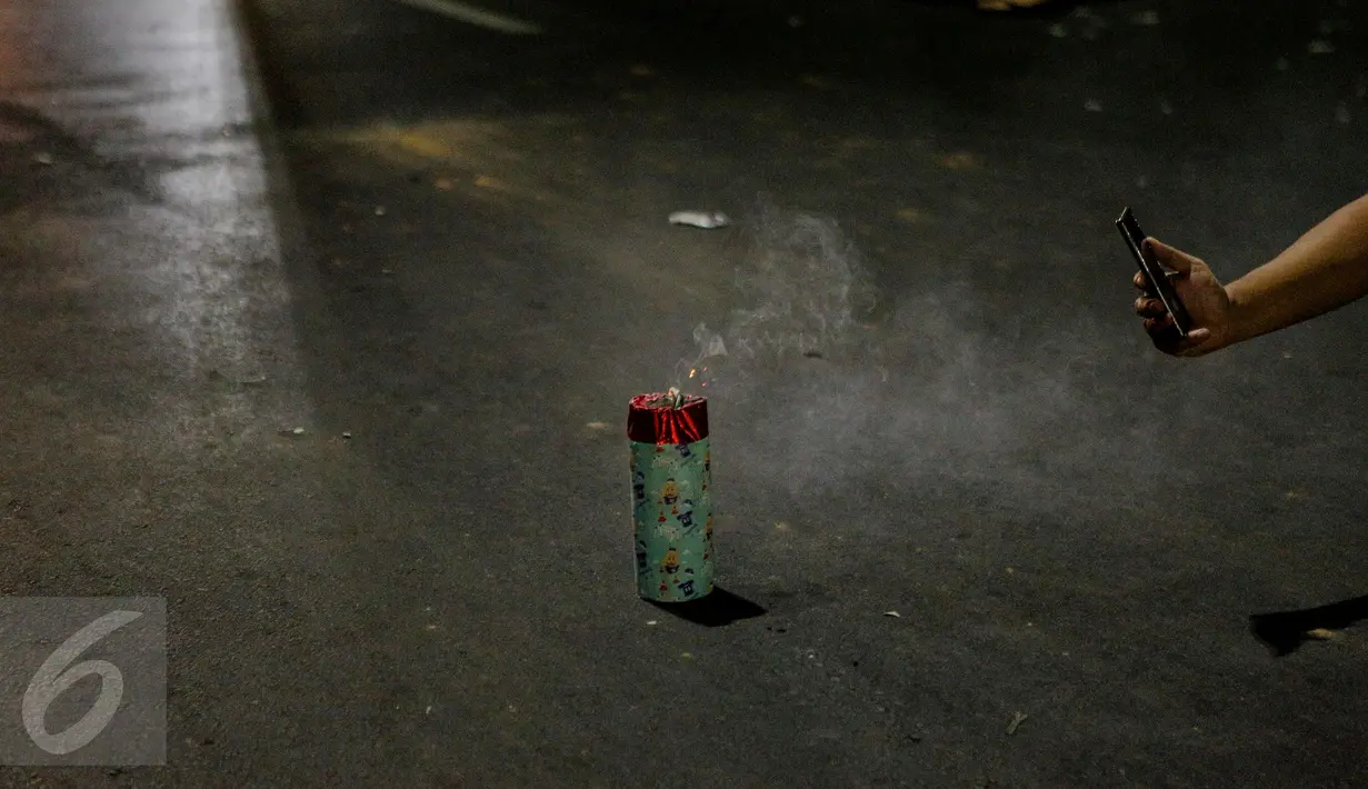 Seseorang memotret petasan saat malam takbir di Jalan Tanah Abang, Jakarta, Kamis (16/7/2015). Pemerintah melalui Kementerian Agama telah menetapkan 1 Syawal 1436H yang jatuh pada tanggal 17 Juli 2015.(Liputan6.com/Faizal Fanani)