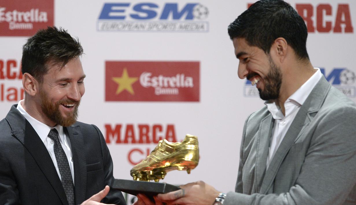Lionel Messi (kiri) menerima penghargaan sepatu emas Eruopa dari rekannya Luis Suarez pada acara Golden Shoe awards 2017 di Antigua Fabrica Estrella Damm, Barcelona, (24/11/2017). (AFP/Josep Lago)