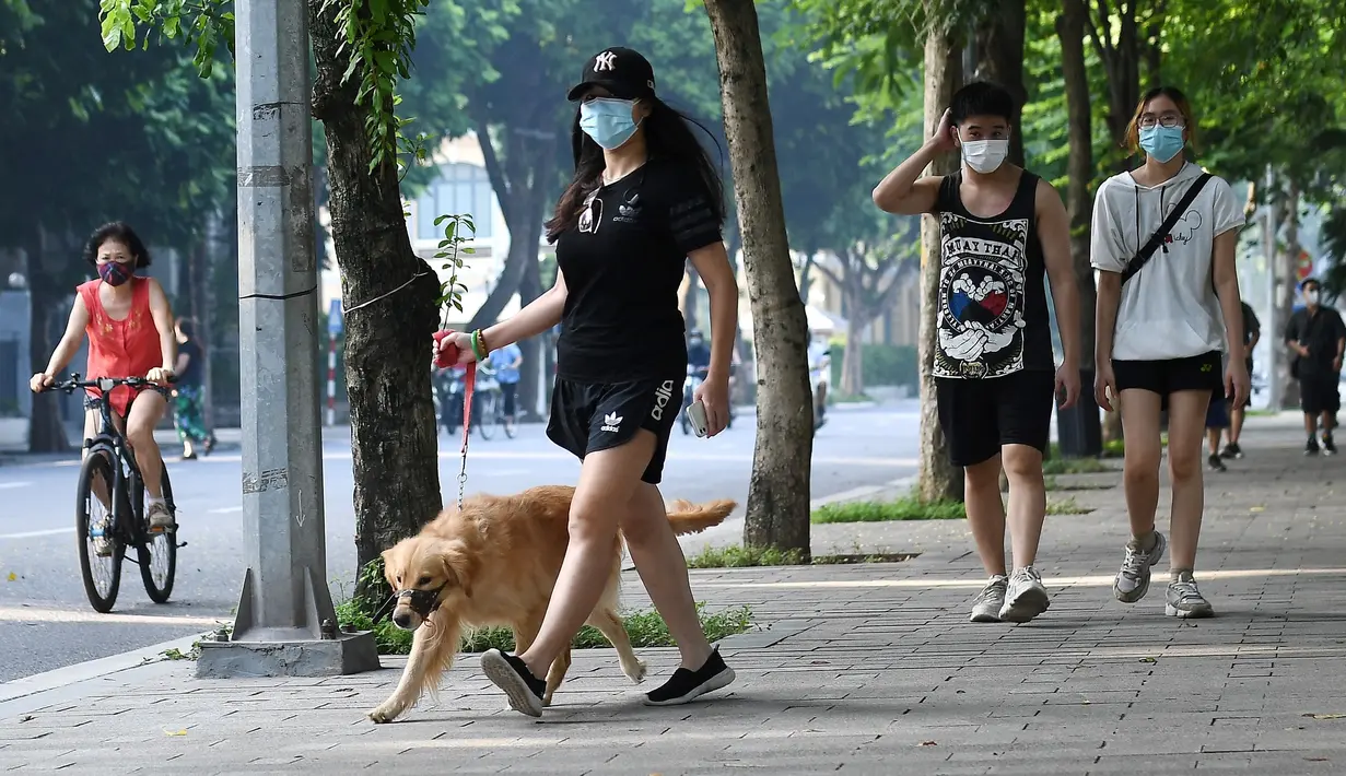 Orang-orang berolahraga dengan berjalan di sepanjang danau Hoan Kiem di Hanoi setelah kegiatan olahraga outdoor diizinkan menyusul pelonggaran pembatasan Covid-19, Selasa (28/9/2021). Sejauh ini, 94 persen dari populasi orang dewasa Hanoi telah menerima satu suntikan vaksin. (Nhac NGUYEN/AFP)