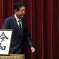 Perdana Menteri Jepang, Shinzo Abe berjalan melintasi plakat nama era baru Kekaisaran Jepang, Reiwa, seusai konferensi pers di Tokyo, Senin (1/4). Reiwa menjadi nama era yang baru yang mengganti Era Heisei seiring persiapan pengunduran diri Kaisar Akihito pada 31 April mendatang. (AP/Eugene Hoshiko)