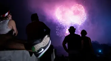 Sejumlah orang menonton kembang api saat perayaan hari kemerdekaan AS di Washington DC (4/7). Ribuan orang berkumpul untuk menyaksikan pertunjukan dan menikmati perayaan tersebut. (AFP Photo/Brendan Smialowski)