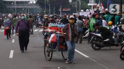Pedangang menawarkan dagangannya kepada massa aksi saat demo penolakan omnibus law di kawasan patung kuda, Jakarta, Selasa (20/10/2020). Para pedagang kaki lima memanfaatkan moment aksi massa untuk mencari ke untungan meskupun sangat membahayakan bagi keselamatan mereka. (Liputan6.com/Angga Yuniar)
