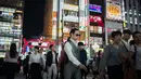 Orang-orang berjalan di distrik Shinjuku, Tokyo pada 22 September 2018. Distrik ini menyuguhkan bangunan bertingkat, department store, toko, restoran, dan tempat hiburan nonstop 24 jam. (AFP PHOTO / Martin BUREAU)