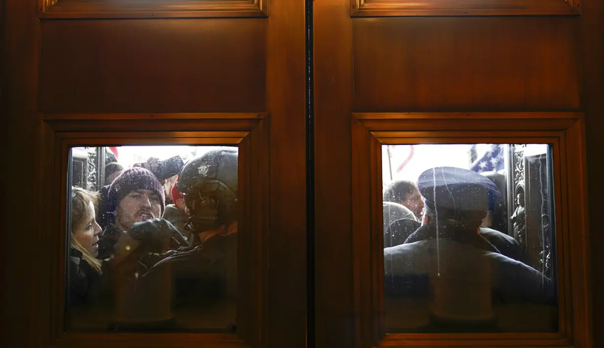 Polisi mencoba menahan pengunjuk rasa yang mencoba masuk ke Gedung Capitol Hill di Washington DC, Amerika Serikat, Rabu (6/1/2021). Donald Trump meminta para pendukungnya untuk "pulang" setelah mereka menyerbu Gedung Capitol Hill. (AP Photo/Andrew Harnik)