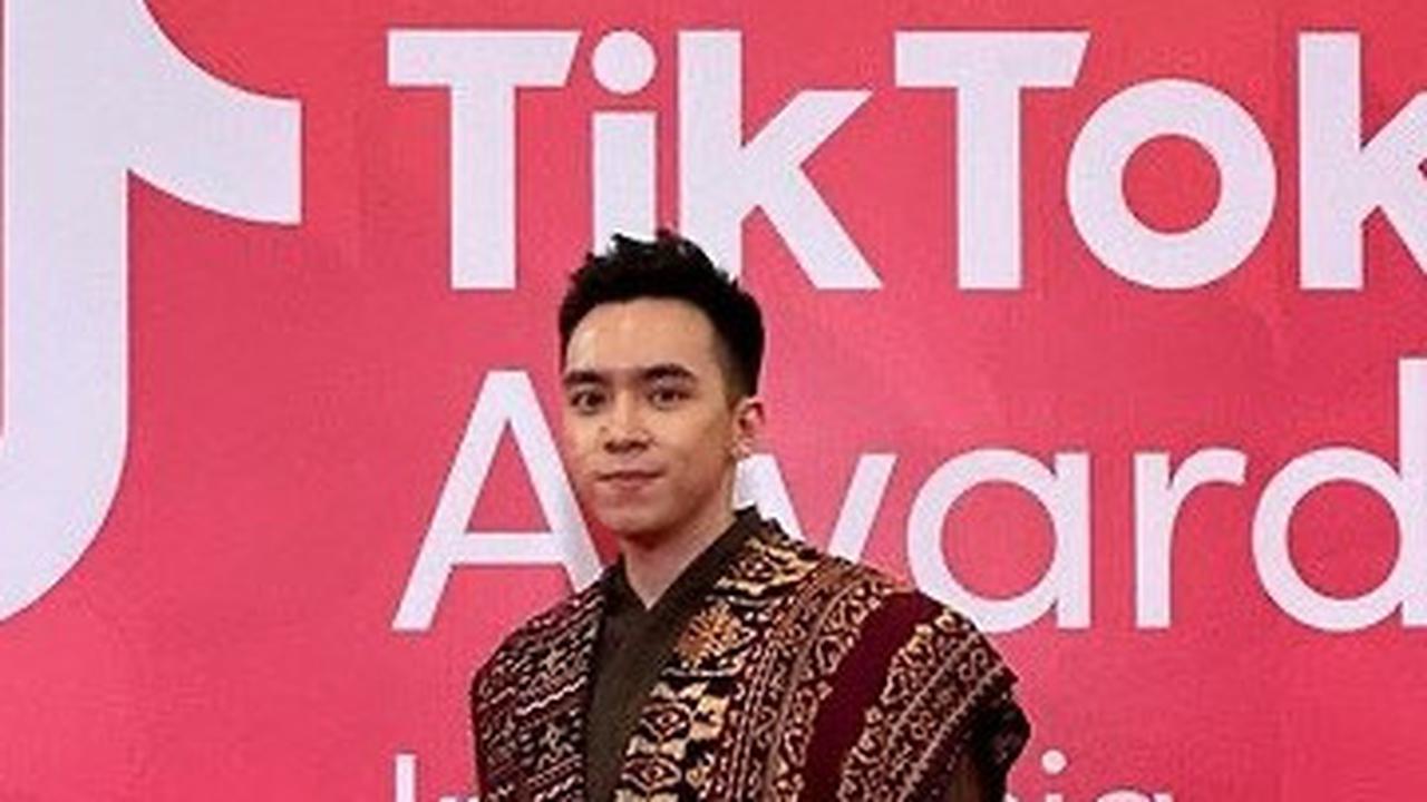 Rey Nathanael tampil dengan gagahnya menggunakan kain Sidan. Busana atasan Rey ini memiliki bentuk asimetris. Di satu sisinya kain dibiarkan menjuntai, sedangkan di sisi lain kain dikombinasikan dengan kain polos berwarna cokelat.