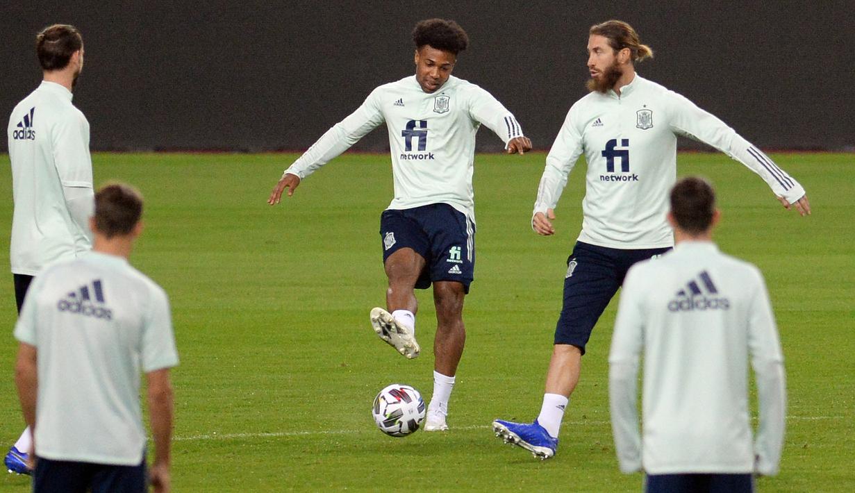 Pemain Spanyol, Adama Traore, berebut bola dengan Sergio Ramos saat sesi latihan jelang menghadapi Jerman pada laga lanjutan Grup 4 UEFA Nations League di Stadion De La Cartuja, Selasa (17/11/2020). Spanyol akan berhadapan dengan Jerman. (AFP/Cristina Quicler)
