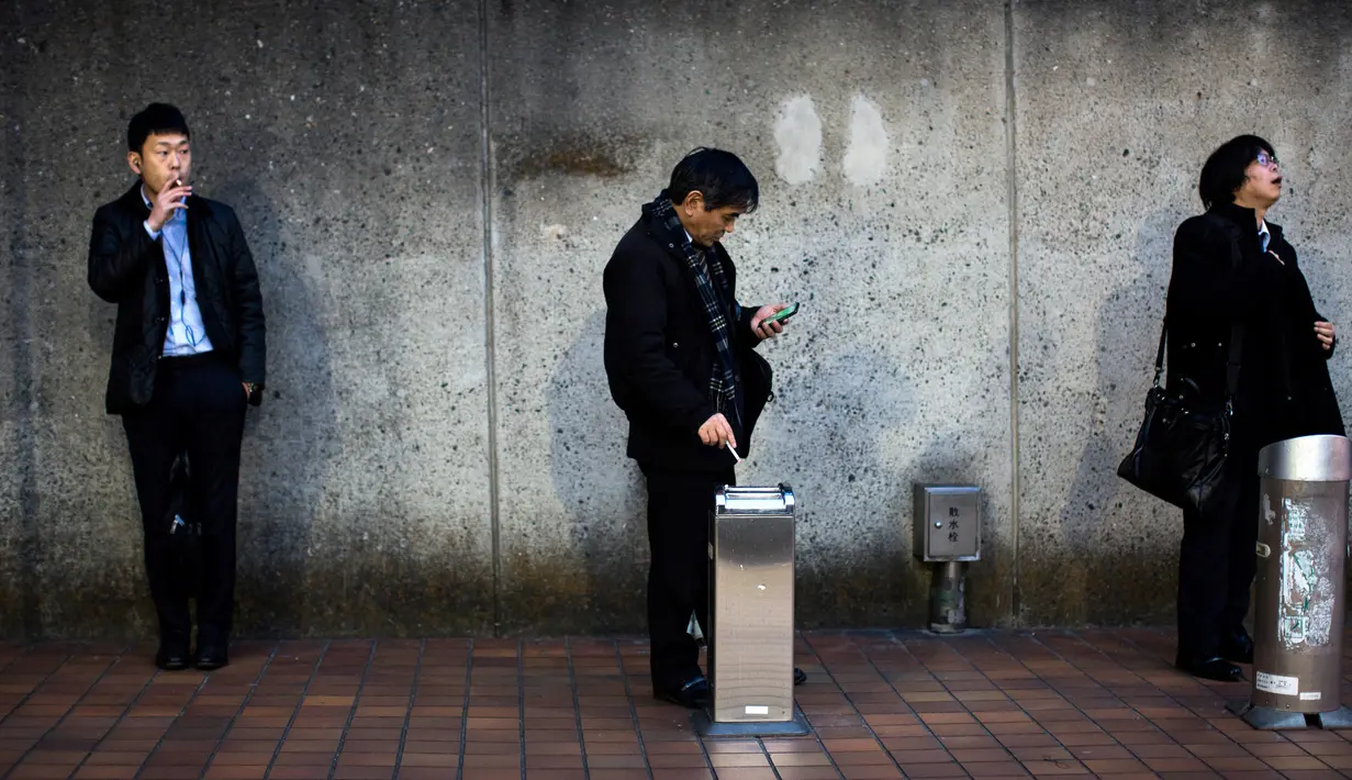 Warga saat merokok di smoking area yang disediakan di Naka-Meguro, Tokyo (10/3). Jepang adalah salah satu negara yang memberlakukan aturan ketat bagi para perokok di tempat umum. (AFP Photo/BEHROUZ MEHRI)
